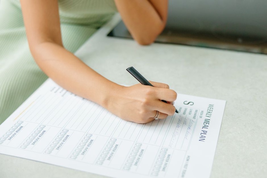 женщина планирует меню на неделю с блокнотом и продуктами